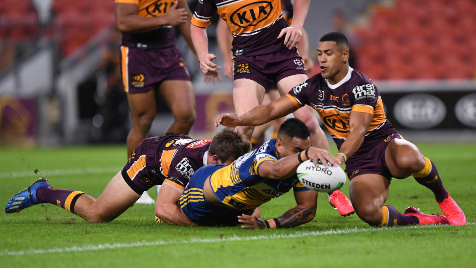 Marata Niukore, center, of the Parramatta Eels reaches out to score a try against the Brisbane Broncos as the National Rugby League resumes play, Thursday, May 28, 2020, in Brisbane, Australia. Two rounds of matches were played in the NRL in March before Australia and New Zealand went into lockdown and closed borders in a bid to slow the spread of COVID-19. (Scott Davis/NRL Photos via AP)