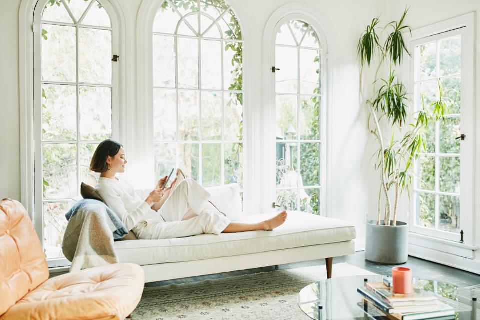 person wearing all white reading a book while relaxing in sunroom