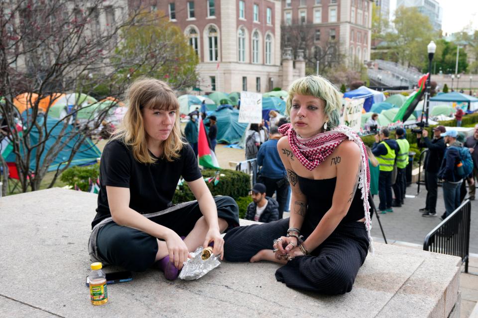 People who did not want to be identified sit outside the encampment, on the campus of Columbia University, Wednesday, April 24, 2024, in New York City. The individual on the right has tattoos in Hebrew lettering and also wears a keffiyeh scarf.