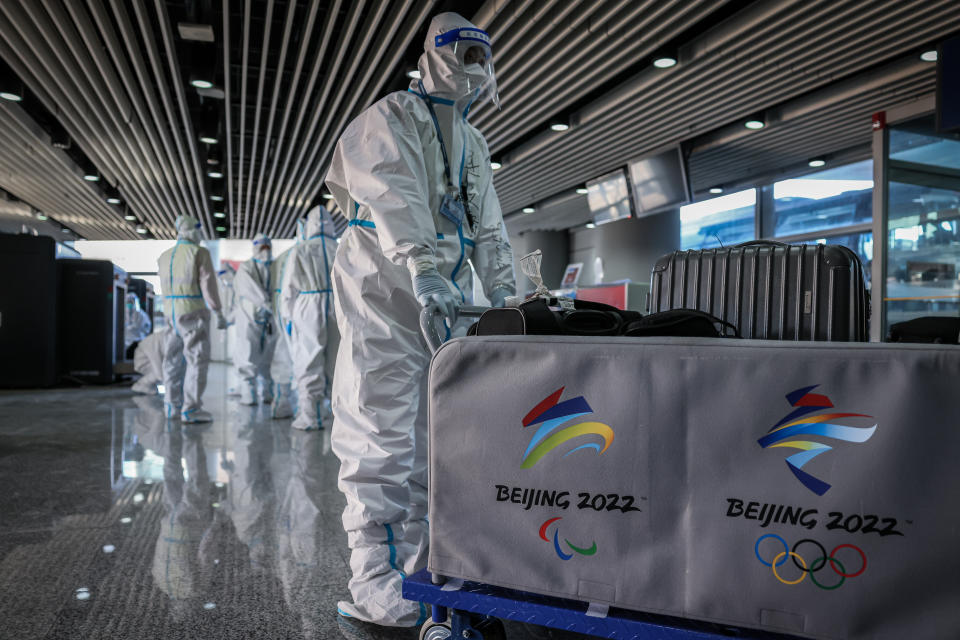 Un trabajador olímpico con un traje de materiales peligrosos lleva equipaje en el Aeropuerto Internacional de Beijing Capital antes de los Juegos Olímpicos de Invierno de 2022 el 2 de febrero de 2022 en Beijing, China.  (Annice Lyn/Getty Images)