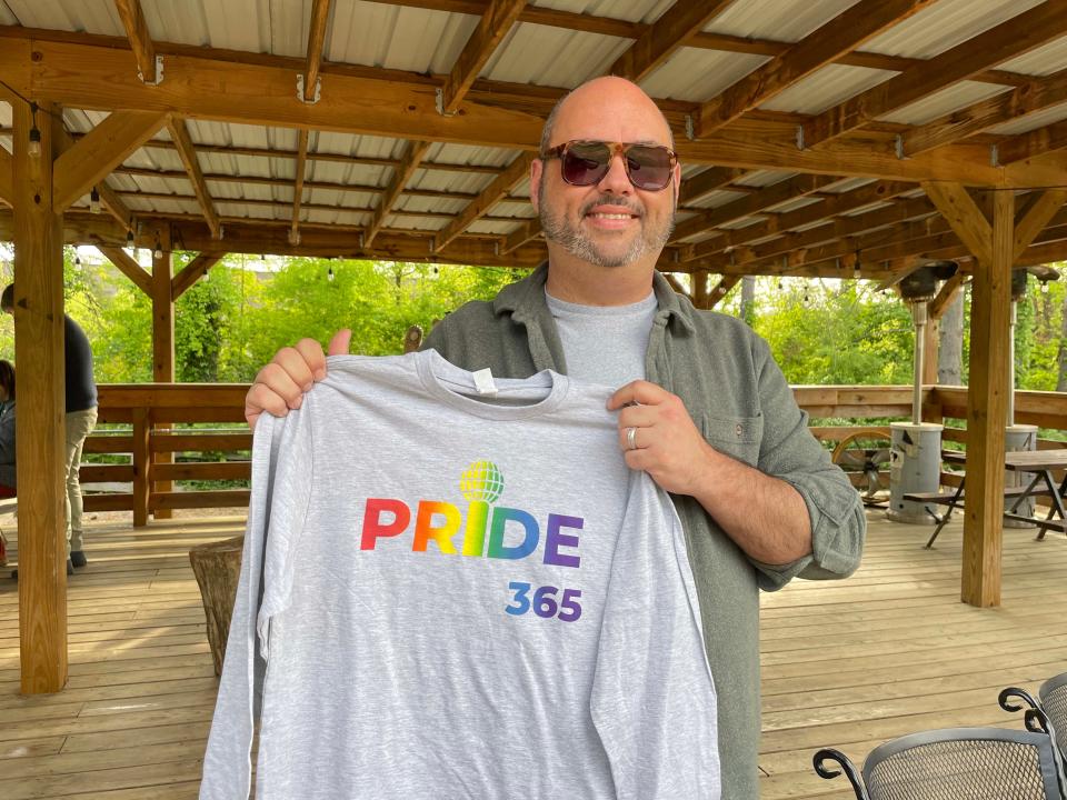 John Camp, executive director and CEO of Knox Pride, shows off a prize T-shirt at the Knox Pride Bingo event at Hey Bear Café Tuesday, April 23, 2024.