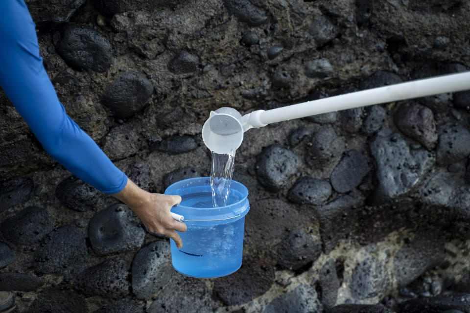 Christiane Keyhani, program coordinator of Hui O Ka Wai Ola, right, puts water into a bucket to test water quality at the Mala Tavern on Friday, Feb. 23, 2024, in Lahaina, Hawaii. (AP Photo/Mengshin Lin)