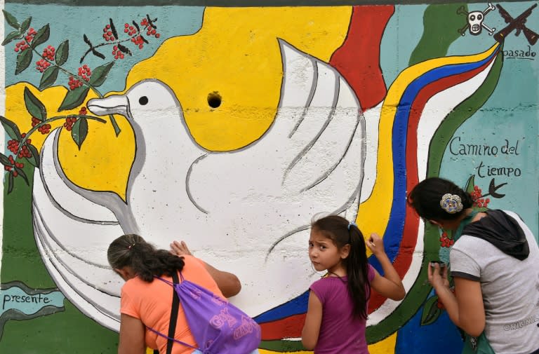 Women and a girl paint a mural alluding to peace on the road leading to Planadas, Tolima department, Colombia on August 26, 2016