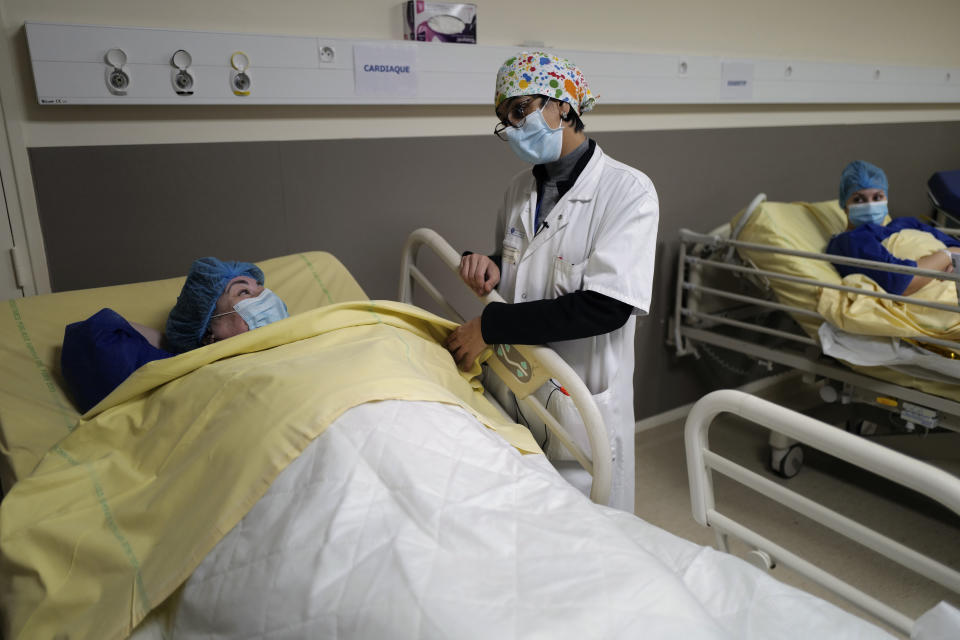 Surgeon Lara Ribeiro Parenti, right, talks to Caroline Erganian, prior to her surgery at Bichat Hospital, AP-HP, in Paris, Wednesday, Dec. 2, 2020. Erganian, 58, hopes to shed more than a third of her weight as a result of having a large part of her stomach cut out and be free of knee and back pain — and of her cane. She prayed in the final weeks that her phone wouldn't ring with news of another delay. (AP Photo/Francois Mori)
