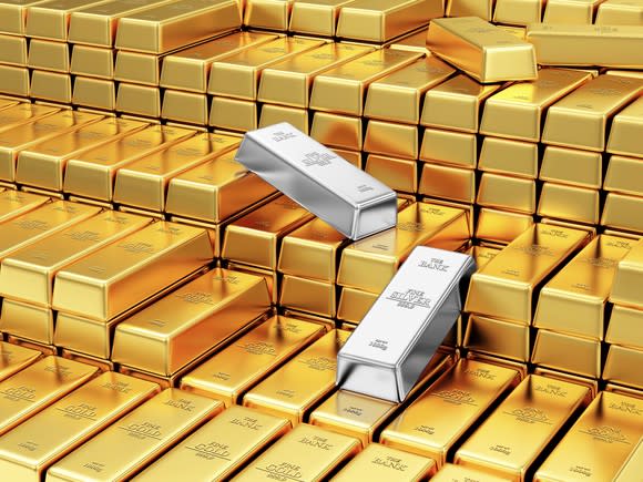 Two silver bars amidst a stack of gold bars.