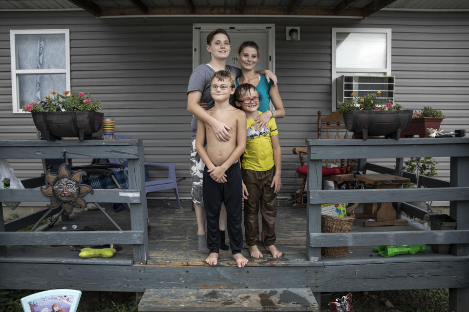 Tasha Lamm, 30, right, poses for a photo with her girlfriend, Alicia Mullins, 22, and Lamm's sons, Donovyn, 8, left, and Gabriel Bonice, 7, in front of their home in Bidwell, Ohio, on Monday, July 27, 2020. "It sucks being poor," says Lamm who is raising her two sons on public assistance. A high-school dropout, she has been promising herself for years that she'd get her equivalency degree. (AP Photo/Wong Maye-E)