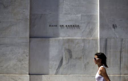 A woman walks past the headquarters of the Bank of Greece in Athens, Greece, August 19, 2015. REUTERS/Stoyan Nenov