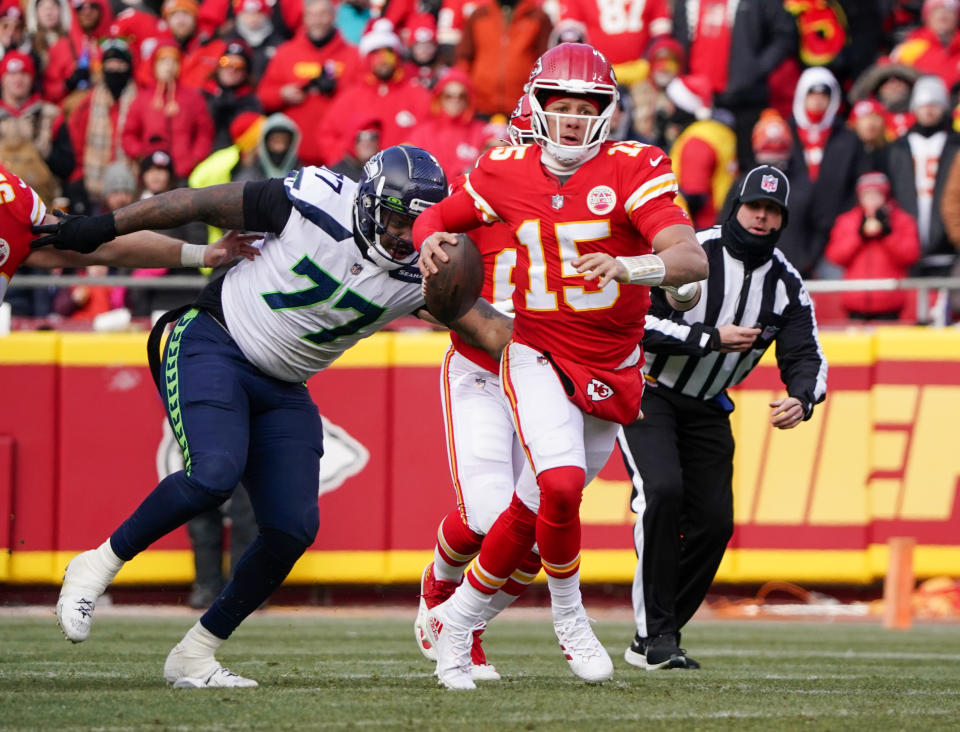 Dec 24, 2022; Kansas City, Missouri, USA; Kansas City Chiefs quarterback Patrick Mahomes (15) looks to pass as Seattle Seahawks defensive tackle Quinton Jefferson (77) attempts the tackle during the second half at GEHA Field at Arrowhead Stadium. Mandatory Credit: Denny Medley-USA TODAY Sports