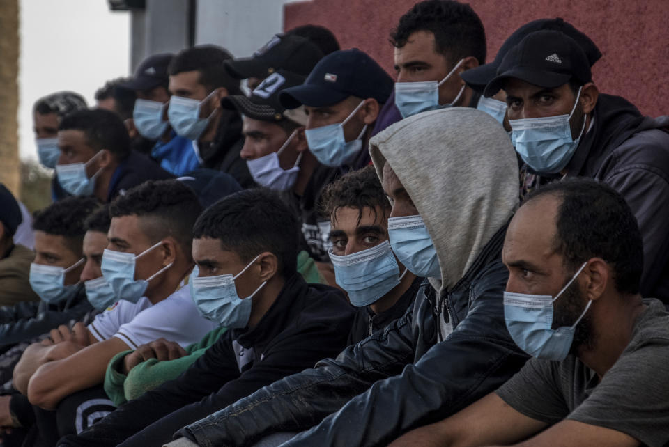 FILE - In this Tuesday, Oct. 20, 2020 file photo, migrants from Morocco sit after arriving at the coast of the Canary Island, crossing the Atlantic Ocean sailing on a wooden boat. Spain’s government is scrambling to manage the steady stream of migrants to its Canary Islands from West Africa by opening a second holding camp, officials said Wednesday Nov. 18, 2020, as political tensions rise in the Atlantic archipelago. (AP Photo/Javier Bauluz, File)