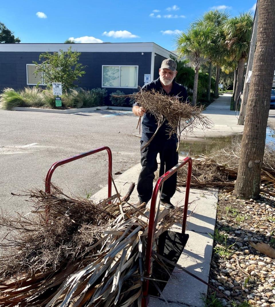 American Business Interiors employee Blane Herndon gathered up fallen palm fronds from Waverly Place parking spaces fronting his building.