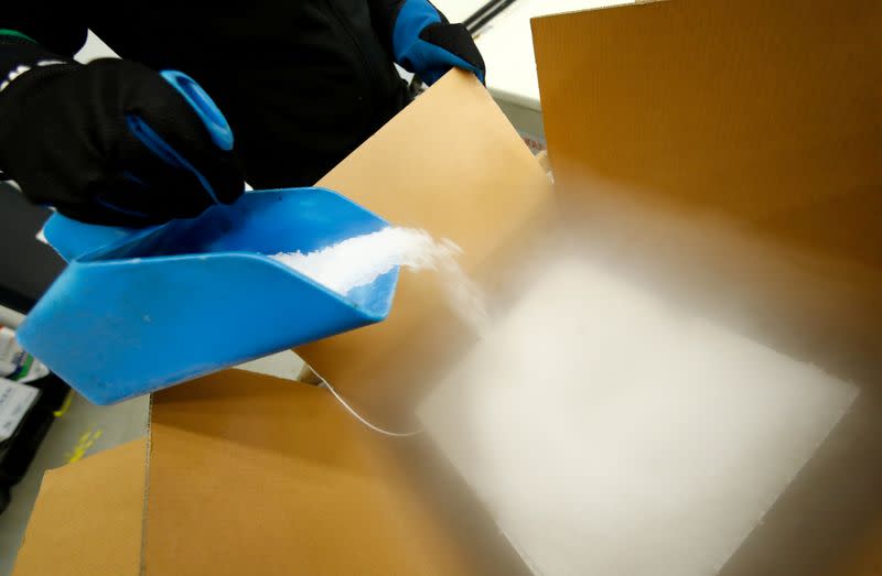 An employee fills an ultra-low temperature container with dry ice to transport vaccines against the coronavirus disease (COVID-19) at a secret storage facility in the Rhein-Main area