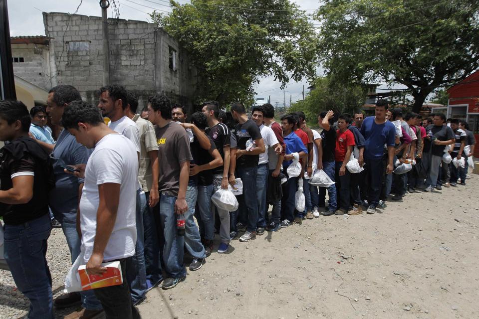 Deportees line up outside a bus at the Care Center for Returning Migrants (CAMR) after arriving on an immigration flight from the U.S., at the international airport in San Pedro Sula June 27, 2014. According to the General Directorate of Migration and Immigration, 20,000 Hondurans were deported by air from the U.S. so far this year 2014. REUTERS/Jorge Cabrera (HONDURAS - Tags: SOCIETY IMMIGRATION)