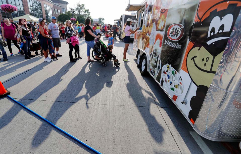 People's shadows etch the street near a food truck at Balloon Glow, Friday, August 19, 2022, in Manitowoc, Wis.