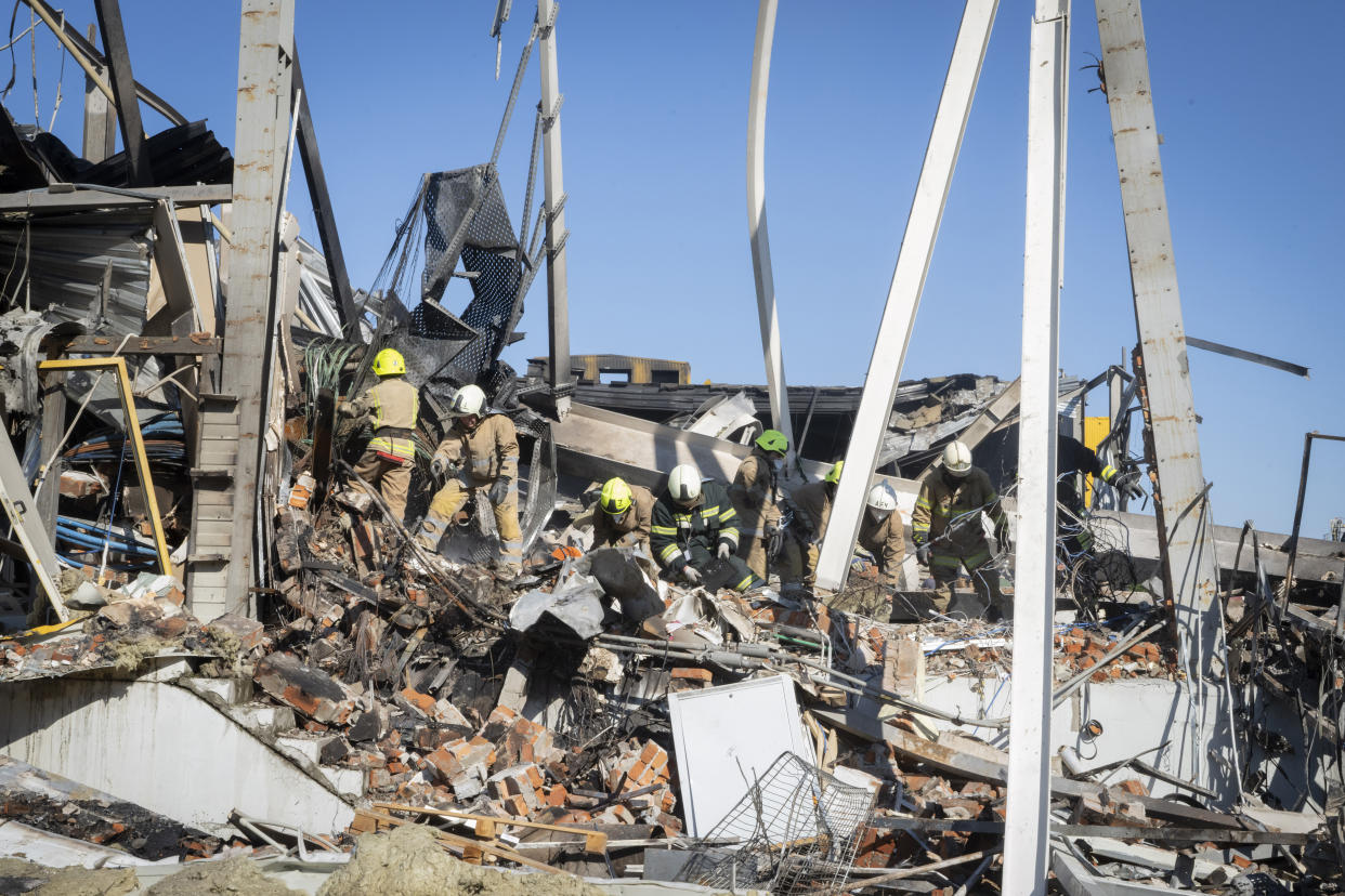 Ukrainian State Emergency Service firefighters work to take away debris at a shopping center burned after a rocket attack in Kremenchuk, Ukraine, Tuesday, June 28, 2022. (AP Photo/Efrem Lukatsky)