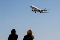 People watch a plane of China Southern Airlines land at Beijing Capital International in Beijing as the country is hit by an outbreak of the novel coronavirus