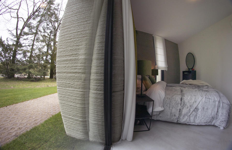 View of the bedroom showing the printer layers in the walls of the 3D-printed 94-square meters (1,011-square feet) two-bedroom bungalow resembling a boulder with windows in Eindhoven, Netherlands, Friday, April 30, 2021. The fluid, curving lines of its gray walls look natural. But they are actually at the cutting edge of housing construction in the Netherlands and around the world. They were 3D printed at a nearby factory. (AP Photo/Peter Dejong)