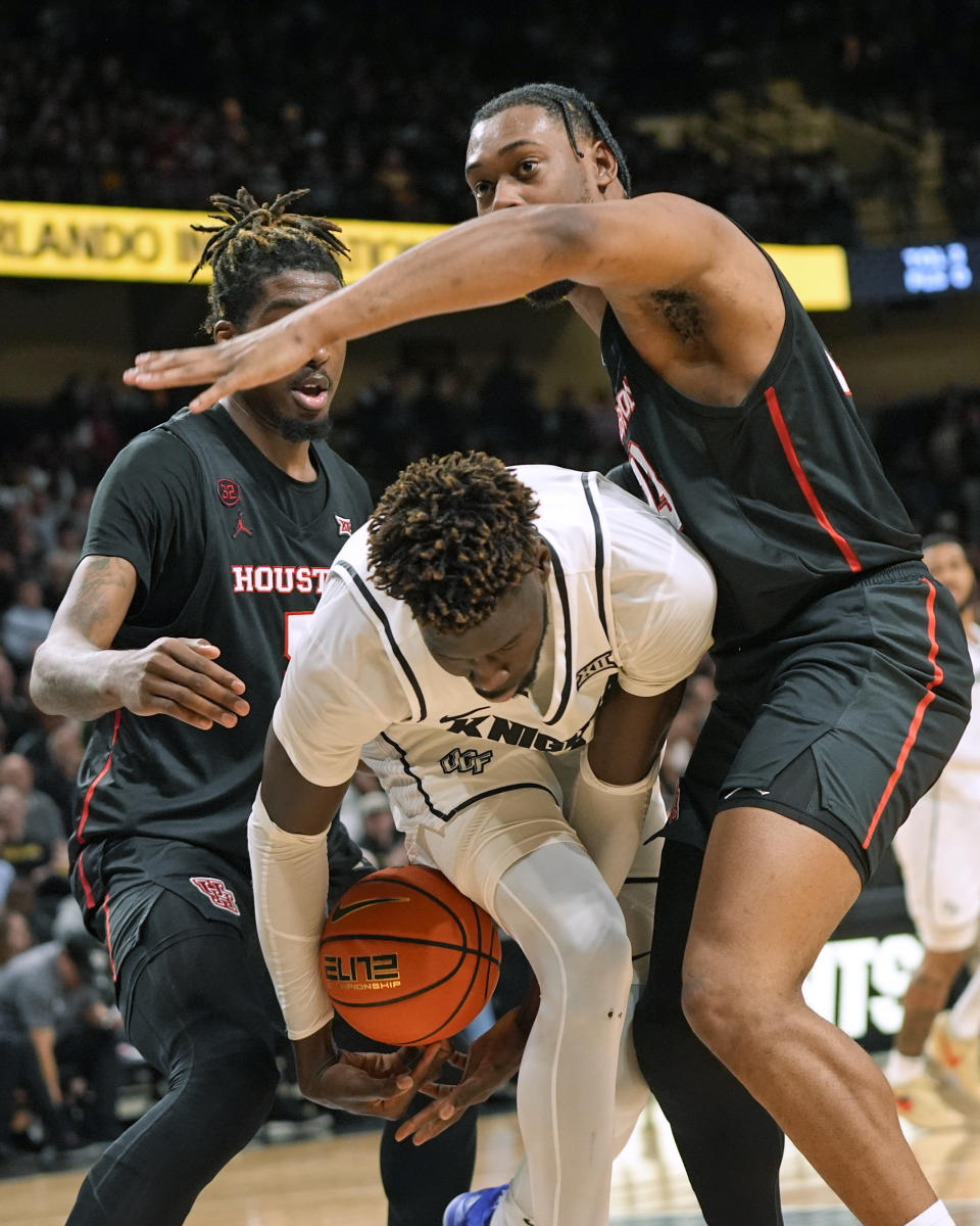 Central Florida forward Thierno Sylla, center, tries to get control of the ball as he gets caught between Houston forward Ja'Vier Francis, left, and forward J'Wan Roberts during the second half of an NCAA college basketball game, Wednesday, March 6, 2024, in Orlando, Fla. (AP Photo/John Raoux)