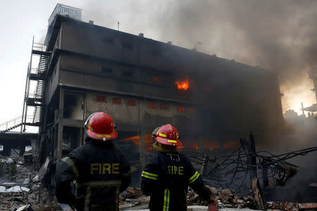 Firefighters stand at the site of a fire at a packaging factory outside Dhaka, Bangladesh, September 10, 2016. To match Insight BANGLADESH-FIRE/ REUTERS/Mohammad Ponir Hossain/File Photo