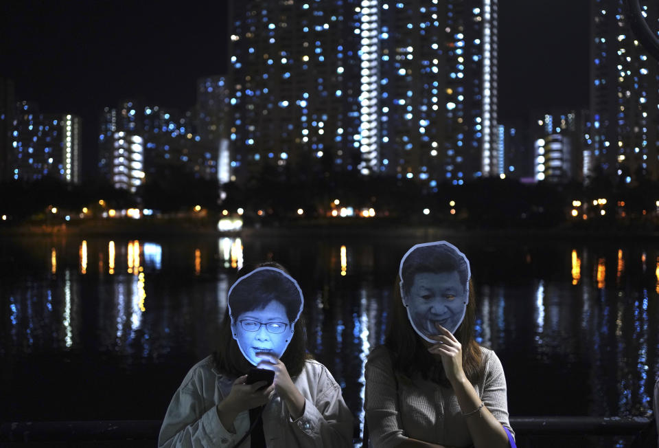 Protesters wear masks of Chinese President Xi Jinping, right, and Hong Kong Chief Executive Carrie Lam during a protest in Hong Kong, Friday, Oct. 18, 2019. Hong Kong pro-democracy protesters are donning cartoon/superhero masks as they formed a human chain across the semiautonomous Chinese city, in defiance of a government ban on face coverings. (AP Photo/Vincent You)