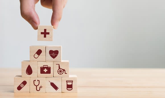 A pyramid of wooden blocks with healthcare icons on them.