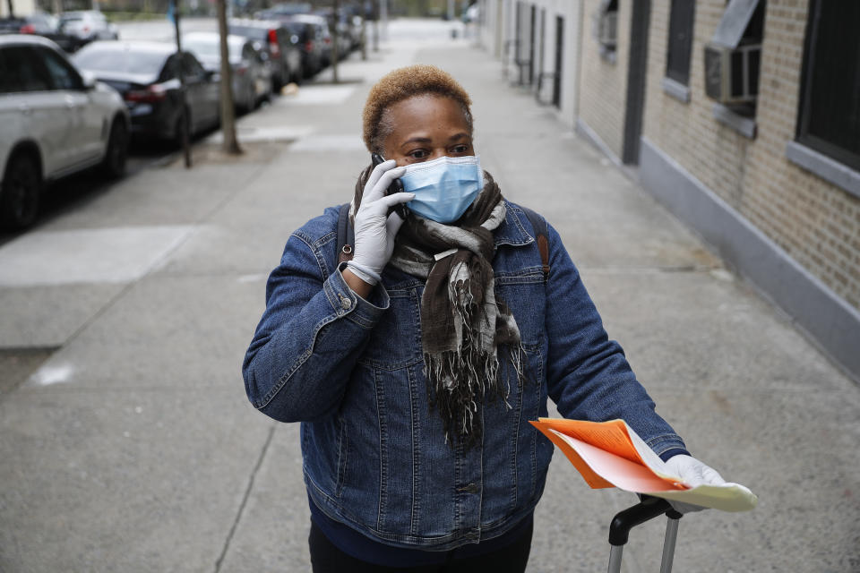 In this Thursday, April 23, 2020 photo, Ruth Caballero, a nurse with The Visiting Nurse Service of New York, speaks with a patient's doctor after a home visit as she makes her rounds in upper Manhattan, Thursday, April 23, 2020, in New York. Home care nurses, aides and attendants, who normally help an estimated 12 million Americans with everything from bathing to IV medications, are now taking on the difficult and potentially dangerous task of caring for coronavirus patients. (AP Photo/John Minchillo)