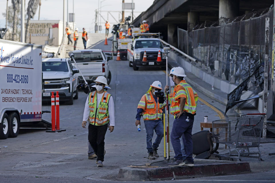 Workers clean the site of a weekend fire which caused the closure of Interstate 10 Monday, Nov. 13, 2023, in Los Angeles. Los Angeles drivers are being tested in their first commute since a weekend fire that closed a major elevated interstate near downtown. (AP Photo/Ryan Sun)