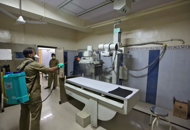 A municipal worker disinfects an X-ray machine inside a government-run hospital to limit the spreading of coronavirus disease (COVID-19), in Mumbai