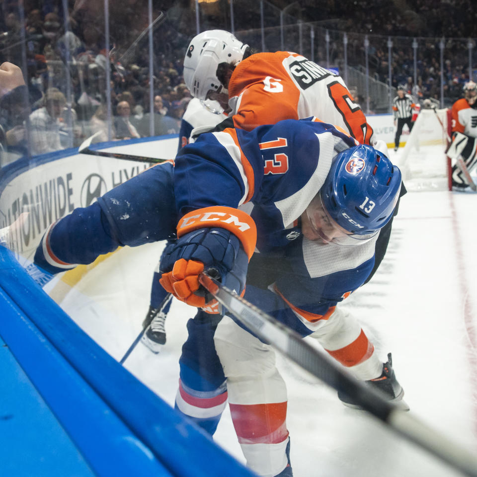 Philadelphia Flyers defenseman Travis Sanheim (6) and against New York Islanders center Mathew Barzal (13) work for the puck along the boards during the second period of an NHL hockey game Saturday, Nov. 25, 2023, in Elmont, N.Y. (AP Photo/Eduardo Munoz Alvarez)