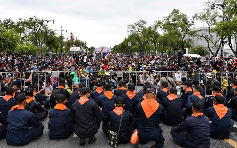 Police sit behind barricades as anti-government protesters take part in a pro-democracy rally in Bangkok  - AFP