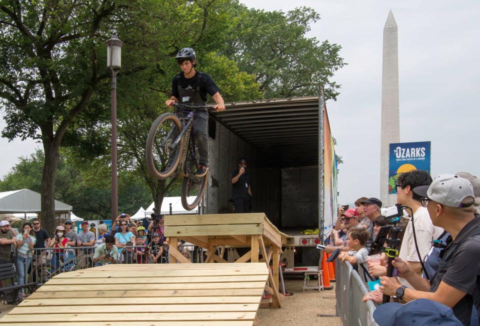 Seth Gebel, owner of Backyard Trail Builds, demonstrates a 100-foot wooden mountain bike structure he built on the National Mall at the Smithsonian Folklife Festival in July 2023.