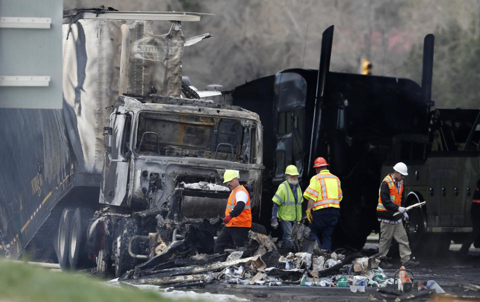 FILE--In this Friday, April 26, 2019, file photograph, workers clear debris from the eastbound lanes of Interstate 70 in Lakewood, Colo., after four motorists died in a fiery pileup involving 28 vehicles at the start of the evening rush hour traffic Thursday, April 25. A truck driver accused of causing the pileup has pleaded not guilty to vehicular homicide and other charges in Jefferson County, Colo., court Thursday, Nov. 21, 2019. The driver's semi-truck hauling lumber plowed into the vehicles as they were caught in a traffic jam on Denver's west side. (AP Photo/David Zalubowski, File)