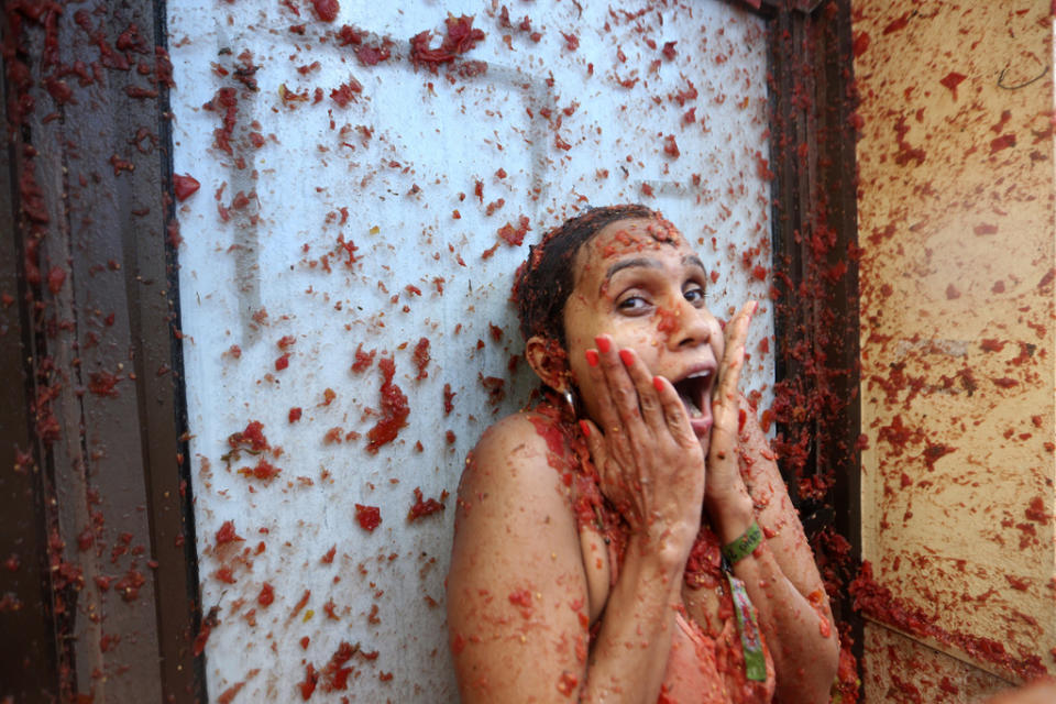 A woman reacts during the annual tomato fight fiesta called” Tomatina” in the village of Bunol near Valencia, Spain, Wednesday, Aug. 30, 2023. Thousands gather in this eastern Spanish town for the annual street tomato battle that leaves the streets and participants drenched in red pulp from 120,000 kilos of tomatoes. (AP Photo/Alberto Saiz)