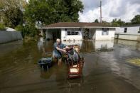 Paul Labatut carries damaged furniture through flood water outside her home in St. Amant, Louisiana. REUTERS/Jonathan Bachman