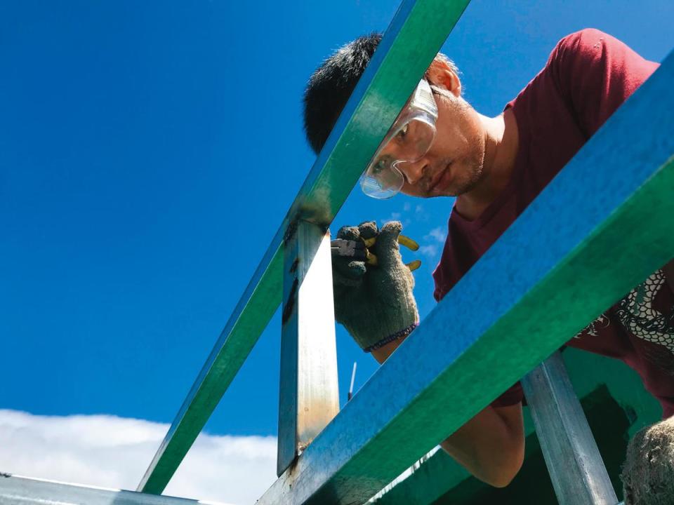 周子飛近來從事防水工程。圖為他正在為客戶家的屋頂鋼架塗刷防水塗料。（陳建彰攝）