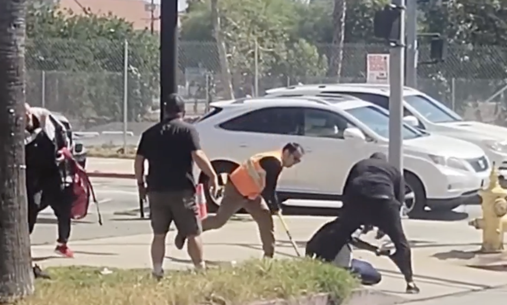 Onlookers surround a man who they allegedly saw abusing a small dog in Hollywood on Monday (NBCLA)