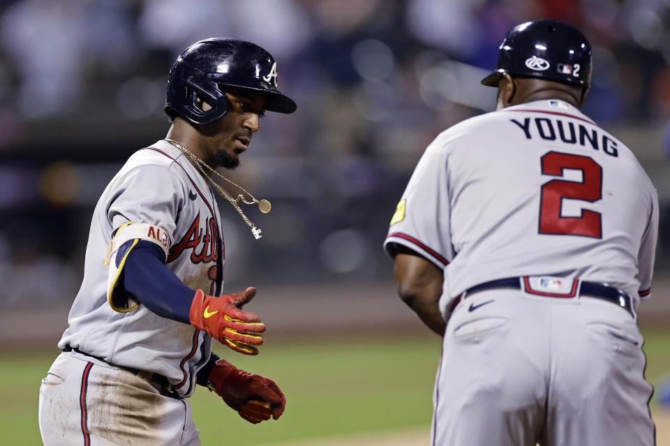 Ozzie Albies, de los Bravos de Atlanta, es felicitado por el coach de primera Eric Young Sr. luego de batear un jonrón de dos carreras en el juego del sábado 12 de agosto de 2023, ante los Mets de Nueva York (AP Foto/Adam Hunger)