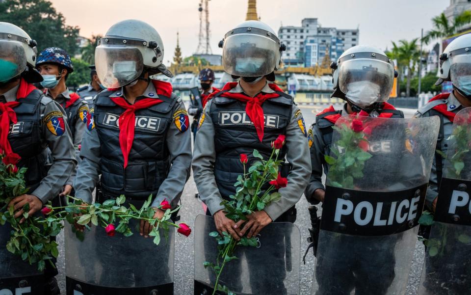 Riot police in Myanmar stand guard with roses given to them by protesters