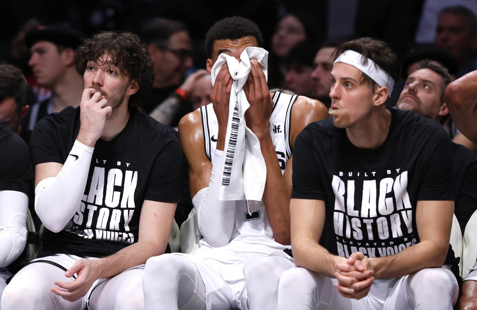 San Antonio Spurs, from left, Cedi Osman, Victor Wembanyama and Zach Collins watch from the bench during the second half of an NBA basketball game against the Brooklyn Nets, Saturday, Feb. 10, 2024, in New York. (AP Photo/Noah K. Murray)