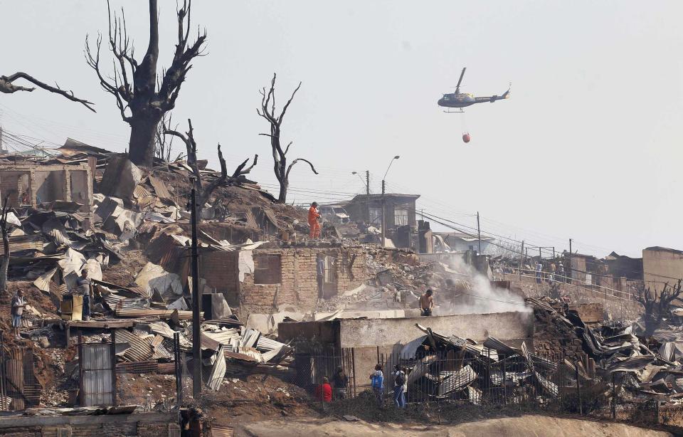 A helicopter assists after a forest fire burned several neighbourhoods in the hills in Valparaiso city, northwest of Santiago, April 13, 2014. At least 11 people were killed and 500 houses destroyed over the weekend by the fire that ripped through parts of Chilean port city Valparaiso, as authorities evacuated thousands and used aircraft to battle the blaze. REUTERS/Eliseo Fernandez (CHILE - Tags: ENVIRONMENT DISASTER TRANSPORT)