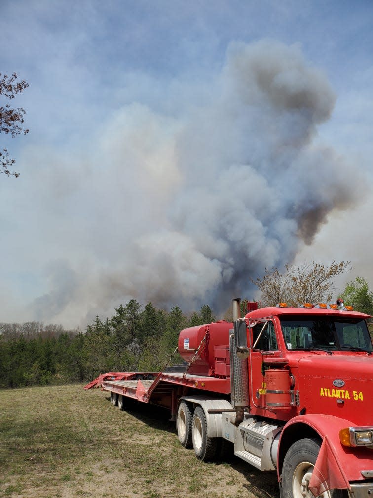 Wildfire smoke is seen behind emergency equipment and vehicles staged to respond to  the Blue Lakes Fire.