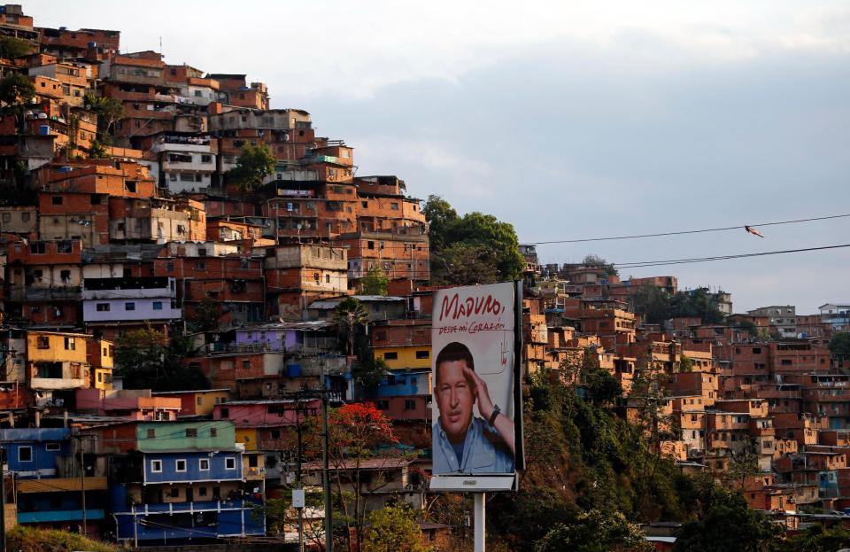 In this March 27, 2014 photo, a poster of Venezuela's late President Hugo Chavez stands in the Petare shanty town of Caracas, Venezuela. Many in Petare, a sprawling hillside slum of crumbling brick buildings on the eastern outskirts of Caracas, have come to rely on Cuban physicians for free health services in a country where private care is too expensive for the poor and public hospitals have a dismal reputation. (AP Photo/Fernando Llano)