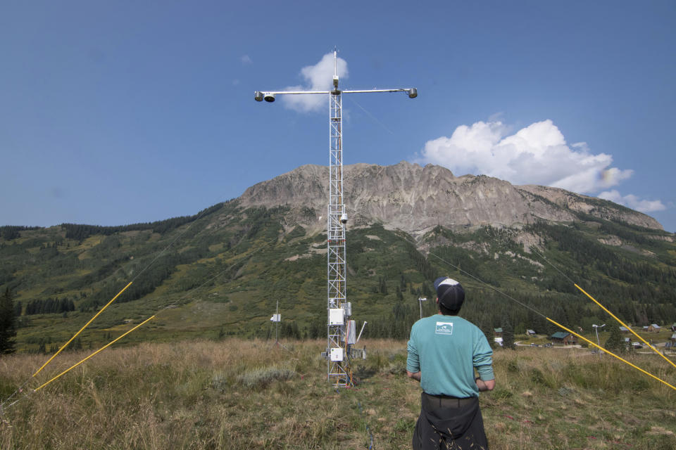 In this Aug. 16, 2021 photo provided Lawrence Berkeley National Laboratory, John Bilberry looks up at an Atmospheric Radiation Measurement instrument tower installed for the Surface Atmosphere Integrated Field Laboratory (SAIL) field campaign in Gothic, Colo. The SAIL campaign will provide insights into mountainous water-cycle processes. Federal scientists are launching an effort to better understand the hydrology in the U.S. West. The U.S. Department of Energy on Tuesday, Aug. 24 announced a new kind of climate observatory near the headwaters of the Colorado River. (David Chu/Lawrence Berkeley National Laboratory via AP)