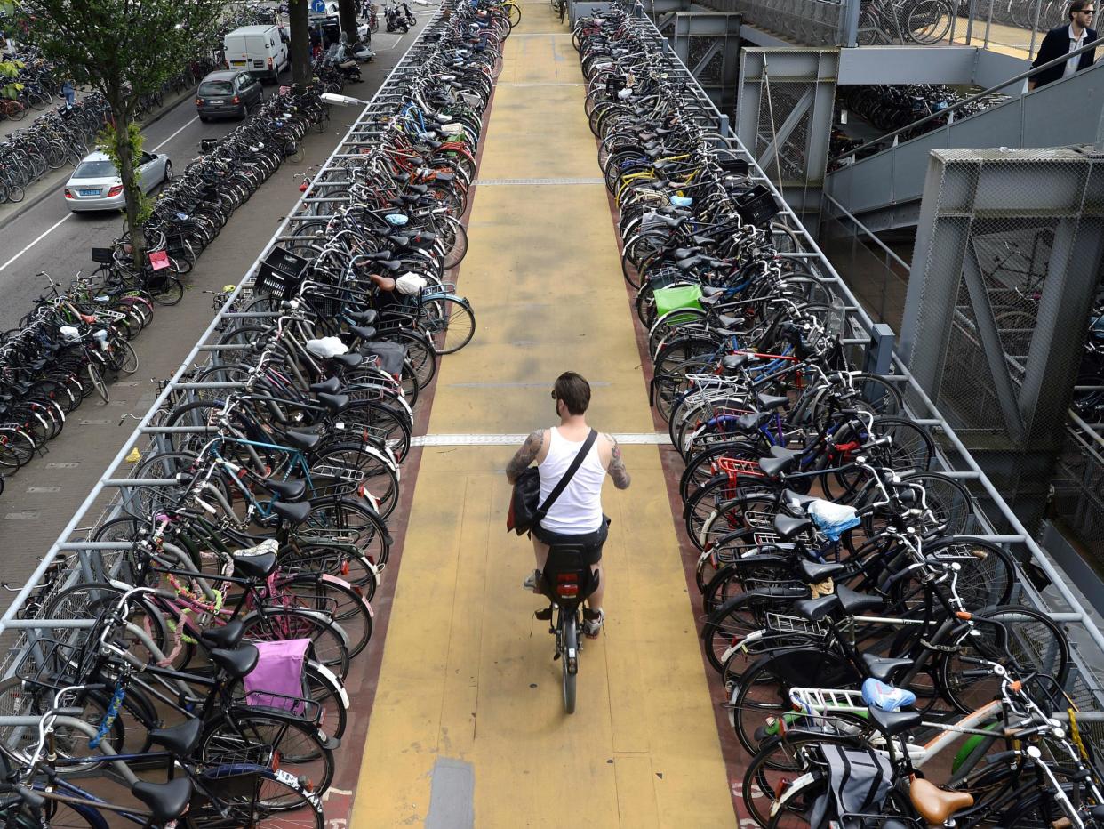 A man rides his bike down from a 3-story bike parking structure in Amsterdam. The government wants to encourage 200,000 more people to commute to work by bike: Getty