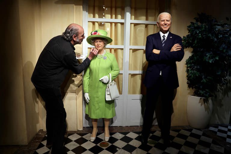 Un artista renueva las estatuas de cera de la reina británica Isabel II, junto a la del presidente estadounidense Joe Biden, en el Musee Grevin de París el 2 de junio de 2022