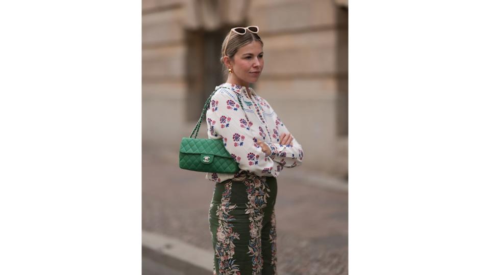 Aline Kaplan s seen wearing beige cat eye sunglasses; chunky golden hoop earrings; several golden necklaces; an outfit from SÃ©zane, consisting of a white long-sleeved shirt with floral pattern and a wide high-waisted pair of trousers in olive with floral pattern and a green leather vintage bag from Chanel on June 07, 2024 in Berlin, Germany. (Photo by Jeremy Moeller/Getty Images)