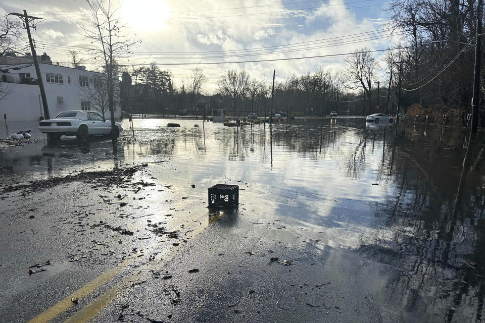 Storm water floods a parking lot and a street in Bronxville, NY, Monday, Dec. 18, 2023. Heavy rain and high winds swept through the Northeast on Monday for the second time in a week, spurring flood warnings, electricity outages, flight cancelations and school closings. (AP Photo/Luke Sheridan)