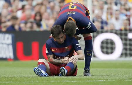 Barcelona's Lionel Messi (L) is comforted by his team mate Gerard Pique as he sits on the pitch after being injured during their Spanish first division soccer match against Las Palmas at Camp Nou stadium in Barcelona, Spain, September 26, 2015. REUTERS/Sergio Perez