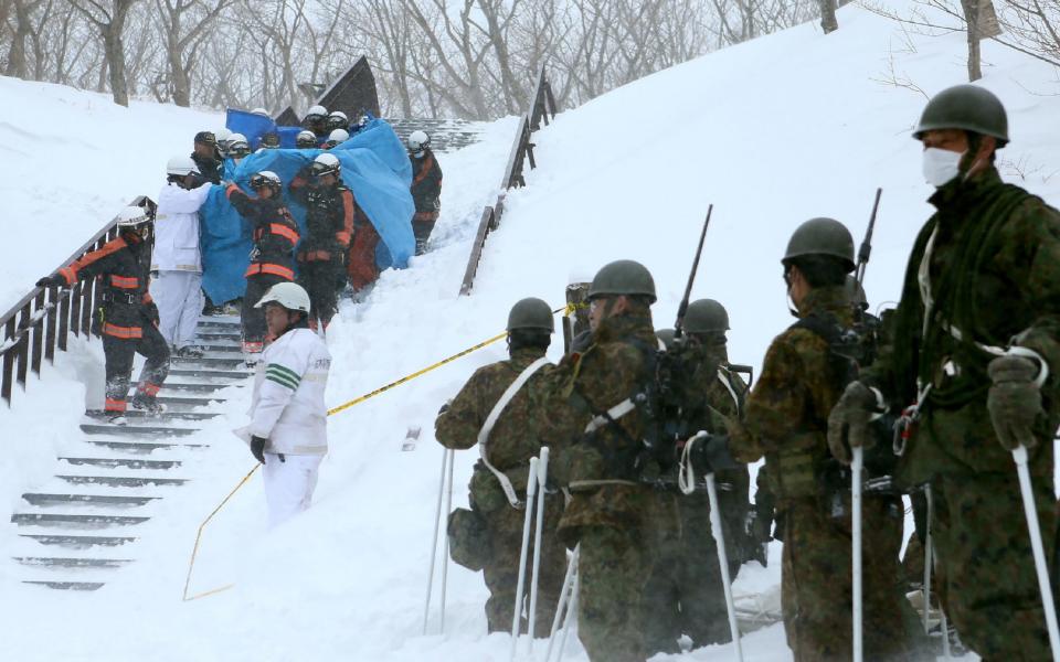 Firefighters carry a survivor they rescued from the site of an avalanche in Nasu town, Tochigi prefecture  - Credit: JIJI PRESS/AFP