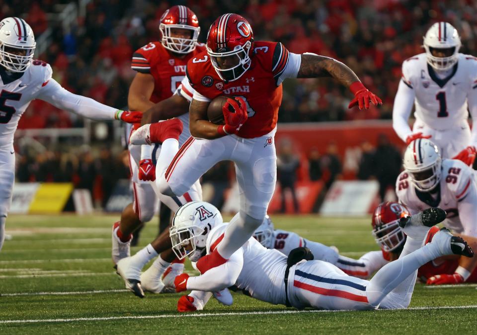 Utah Utes running back Ja’Quinden Jackson, wearing red, is tripped up by Arizona Wildcats safety Christian Young.