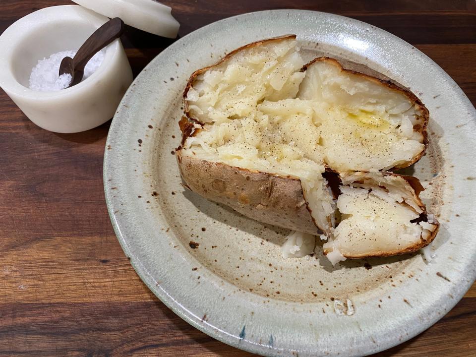 Jacket potato on beige plate with salt beside it